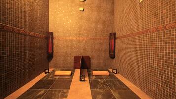 A bathroom with tiled walls, a clock, and two towel racks.