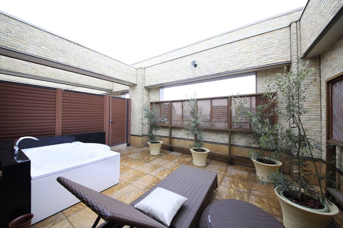 A spa area with a hot tub, lounge chairs, and potted plants.