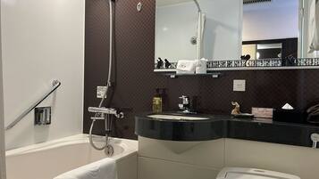 Un baño con bañera, inodoro, lavamanos y espejo.