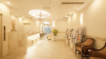 A hotel lobby with a reception desk, seating area, and a chandelier.