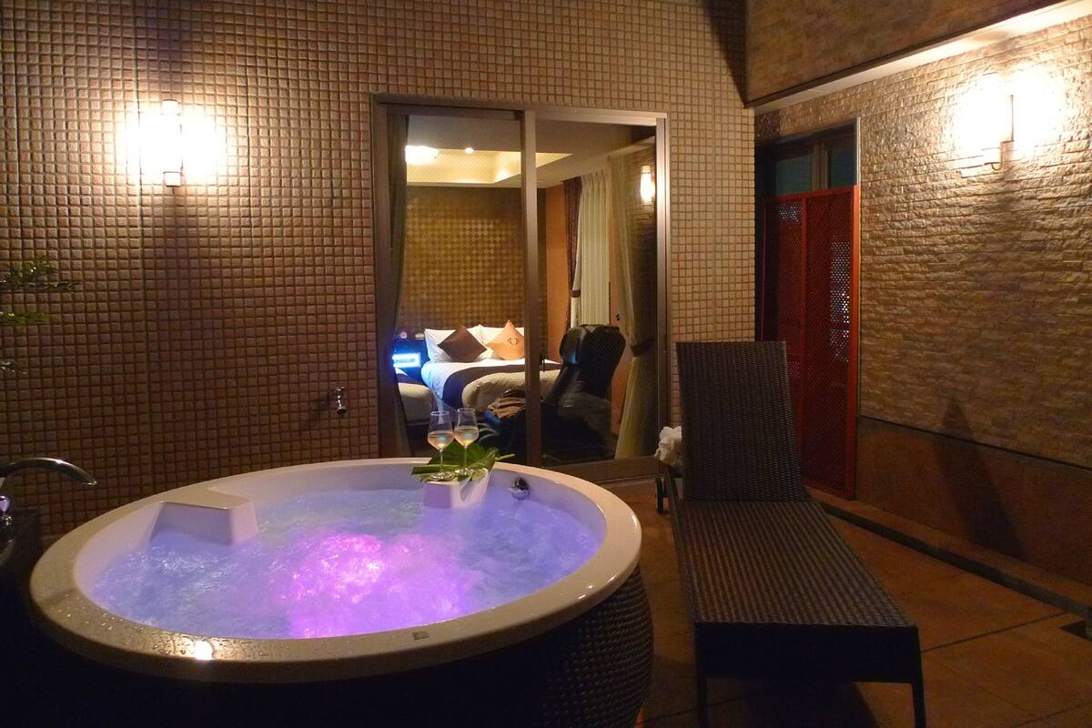 A hot tub with a view of a bedroom through a glass door.
