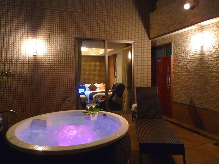 A hot tub with a view of a bedroom through a glass door.