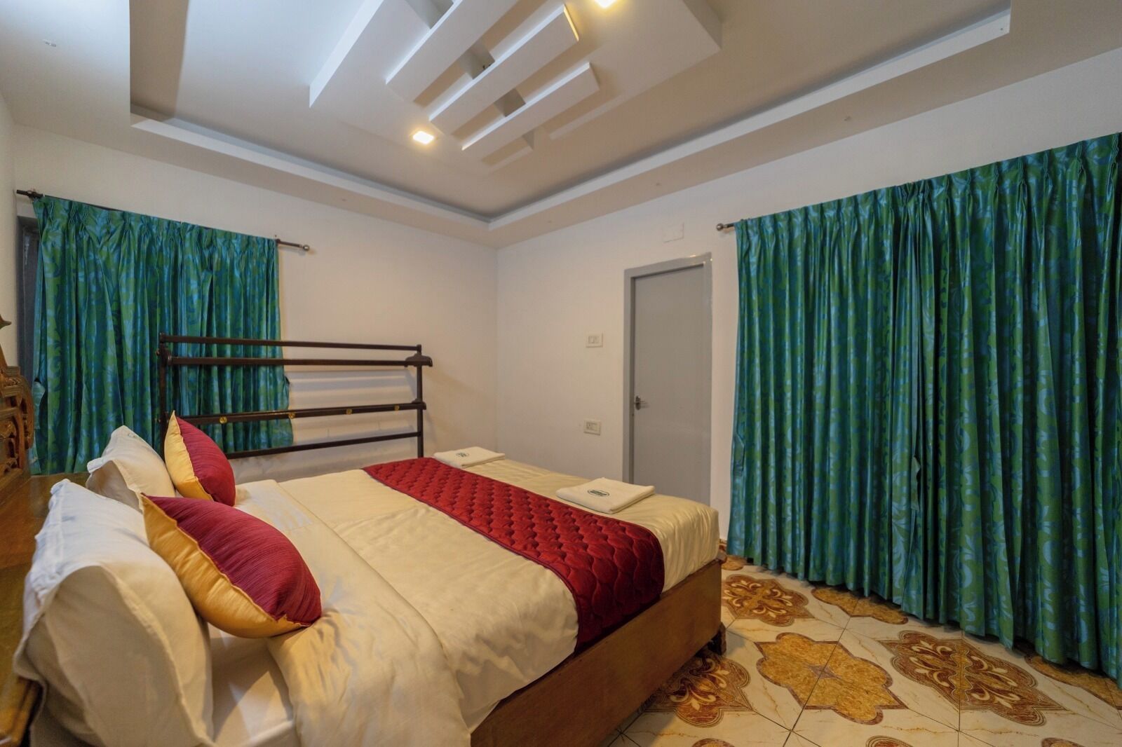 A bedroom with a bed, curtains, and a door.