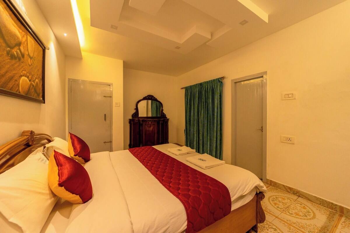 A hotel room with a large bed, a wooden headboard, a mirror, a wardrobe, and a green curtain.
