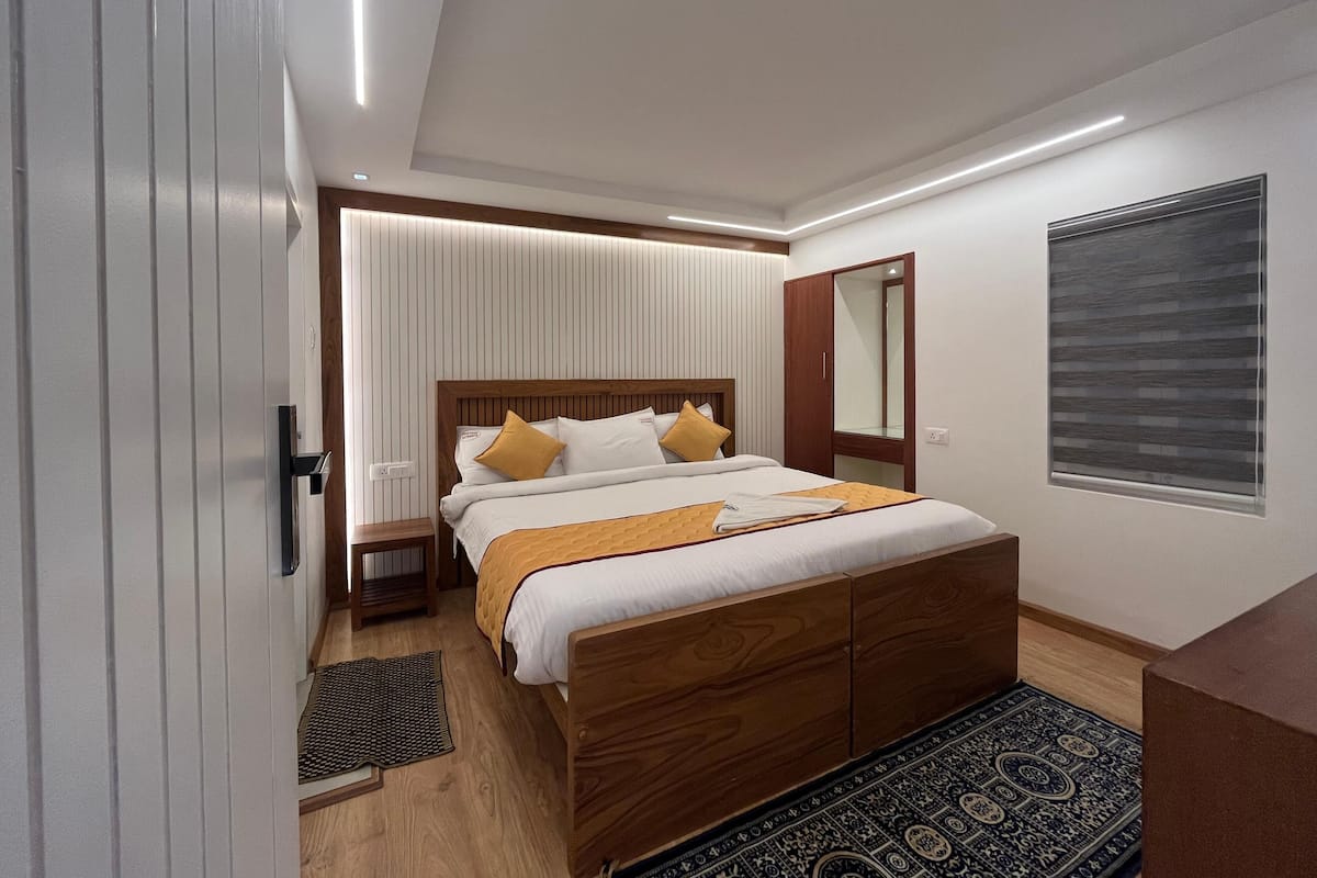 A modern bedroom with a wooden bed, white bedding, and a patterned rug.