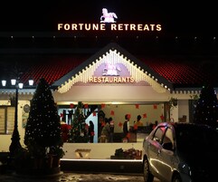 Een gebouw met een bord waarop 'FORTUNE RETREATS RESTAURANTS' staat, en een kerstboom ervoor.