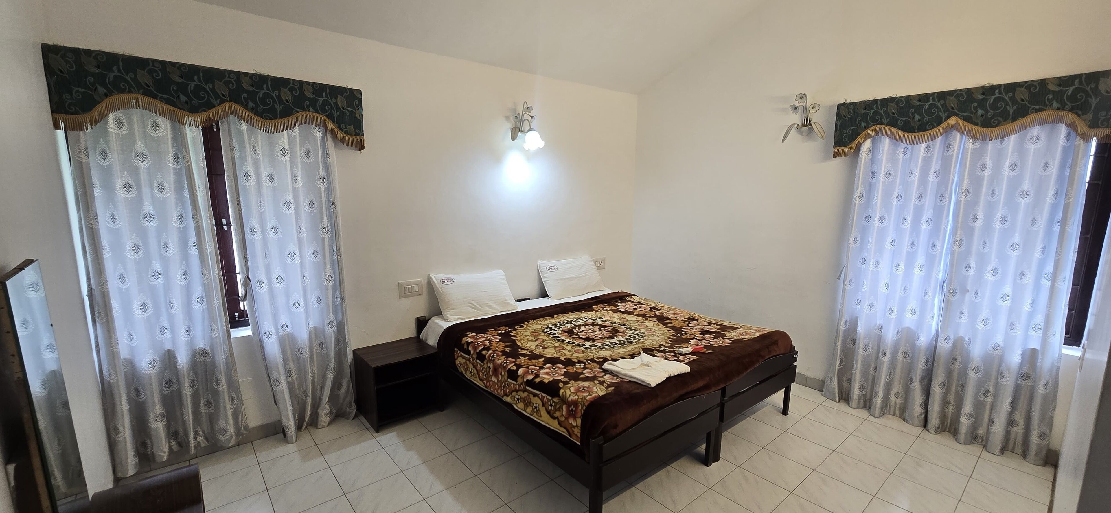 Un dormitorio con cama, mesitas de noche y cortinas.