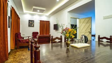 A conference room with a wooden table, chairs, a vase with flowers, and a television on the wall.