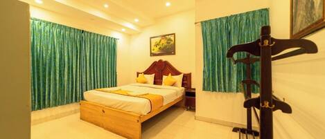 A bedroom with a wooden bed, green curtains, a painting on the wall, and a guitar stand.
