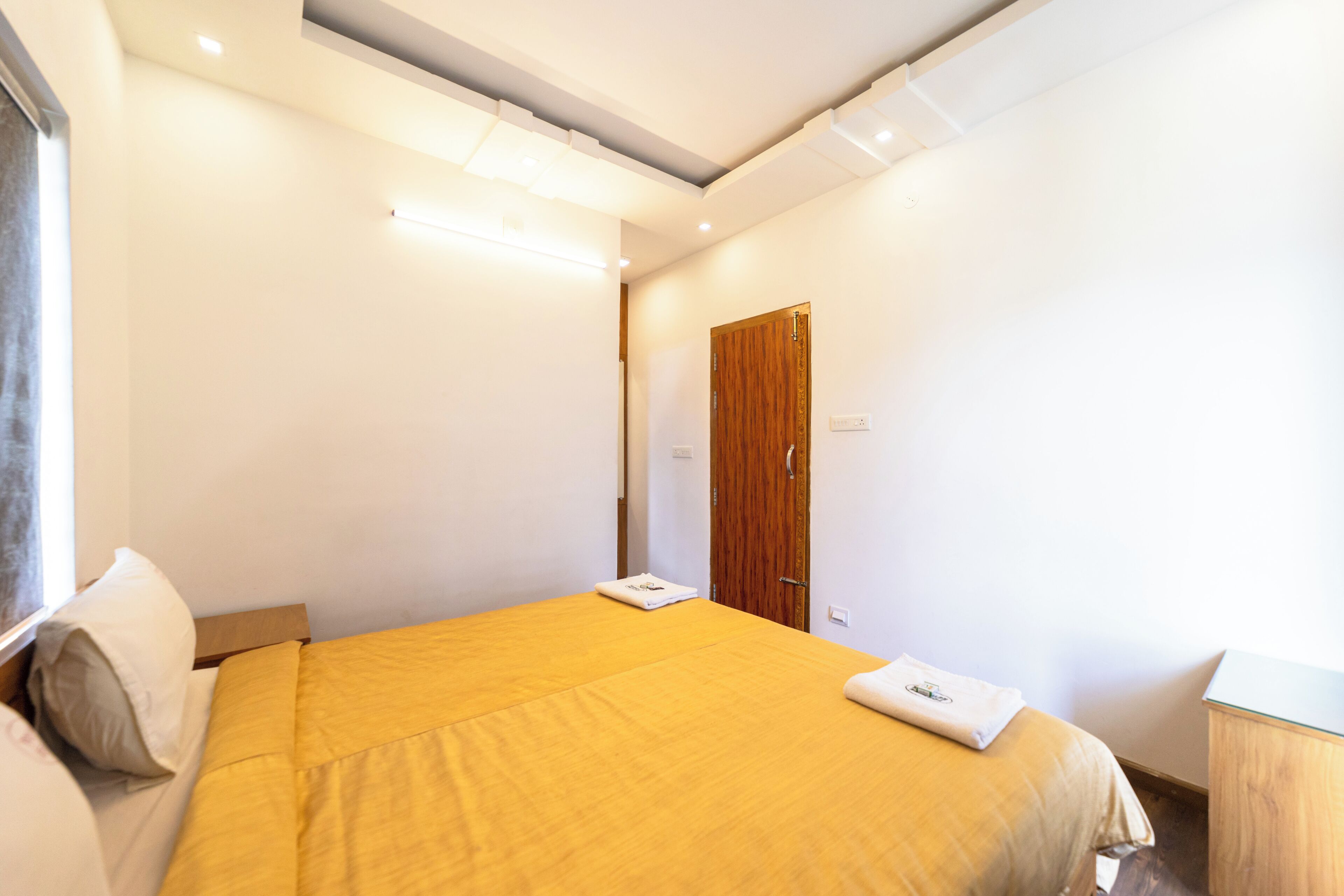 Una habitación de hotel con una cama grande, un armario de madera y una mesita de noche.