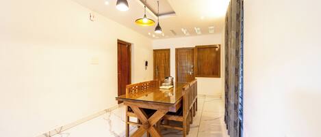 A dining area with a glass-top table, wooden chairs, and pendant lighting.