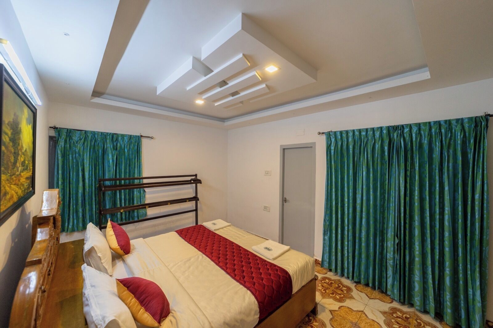 Un dormitorio con cama, escritorio y silla. Se observa una puerta y una ventana con cortinas.