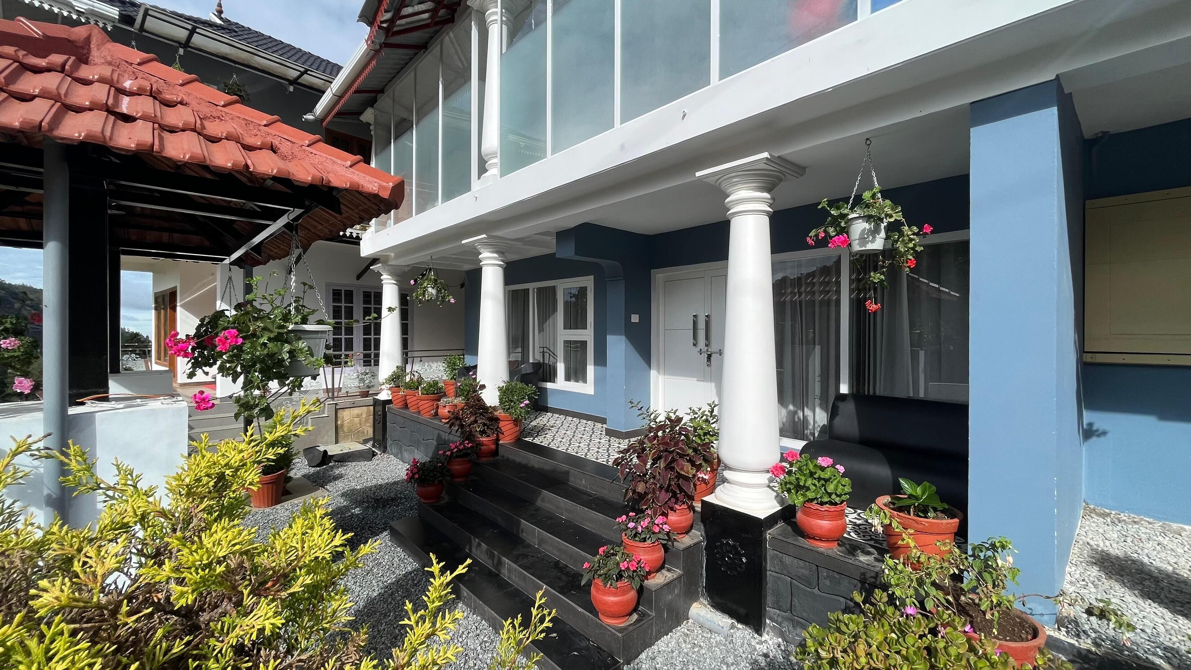 A house with a blue exterior, white columns, and a tiled porch.