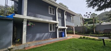 A two-story building with a dark facade, white trim, and a small balcony.