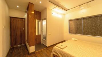 A bedroom with a wooden wardrobe, a bed with a white bedspread, and a window with a patterned view.