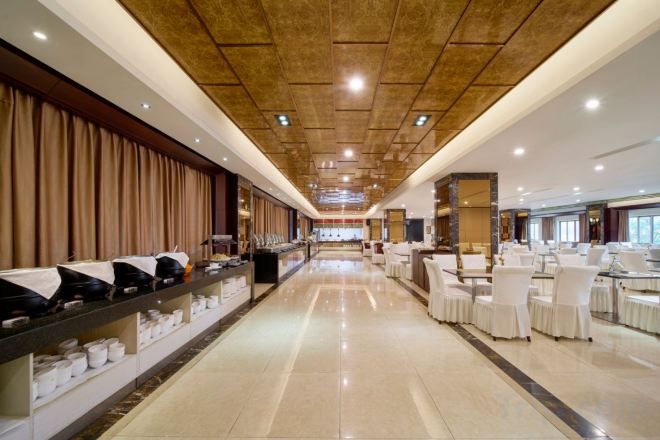 A long corridor with a buffet on the left and a dining area on the right, featuring a high ceiling and modern decor.