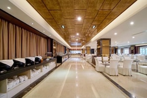 A long corridor with a buffet on the left and a dining area on the right, featuring a high ceiling and modern decor. - WOW HOTEL (Jinhua)