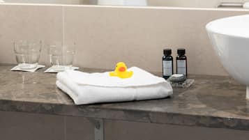 A bathroom with a marble countertop, a white towel, two small bottles, and a glass.