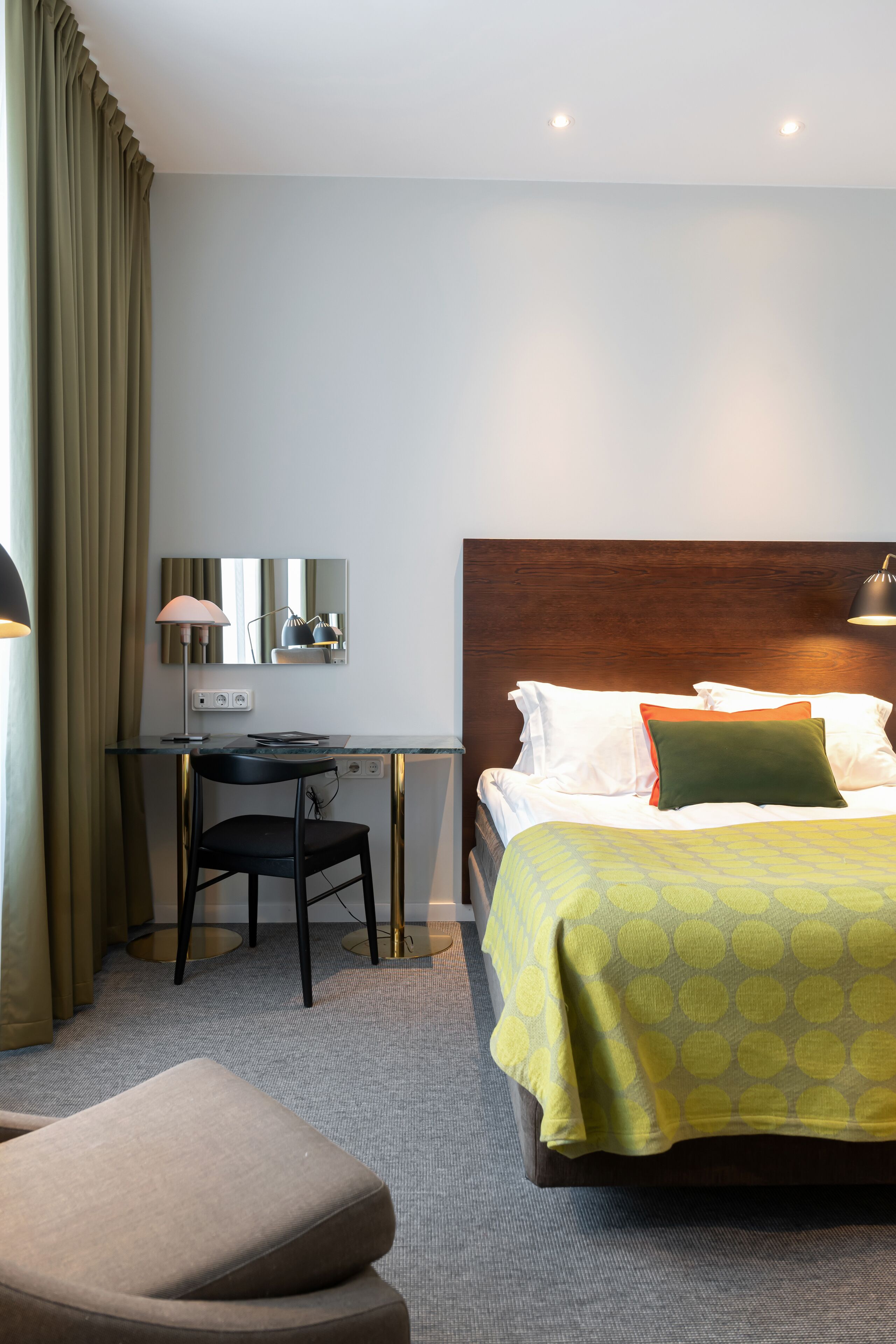 Una habitación de hotel con cama, escritorio, silla y lámpara.
