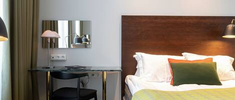 Una habitación de hotel con cama, escritorio, silla y lámpara.