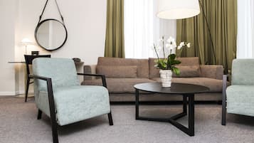 A modern living room with a sofa, two armchairs, a coffee table, a round mirror, and a lamp.