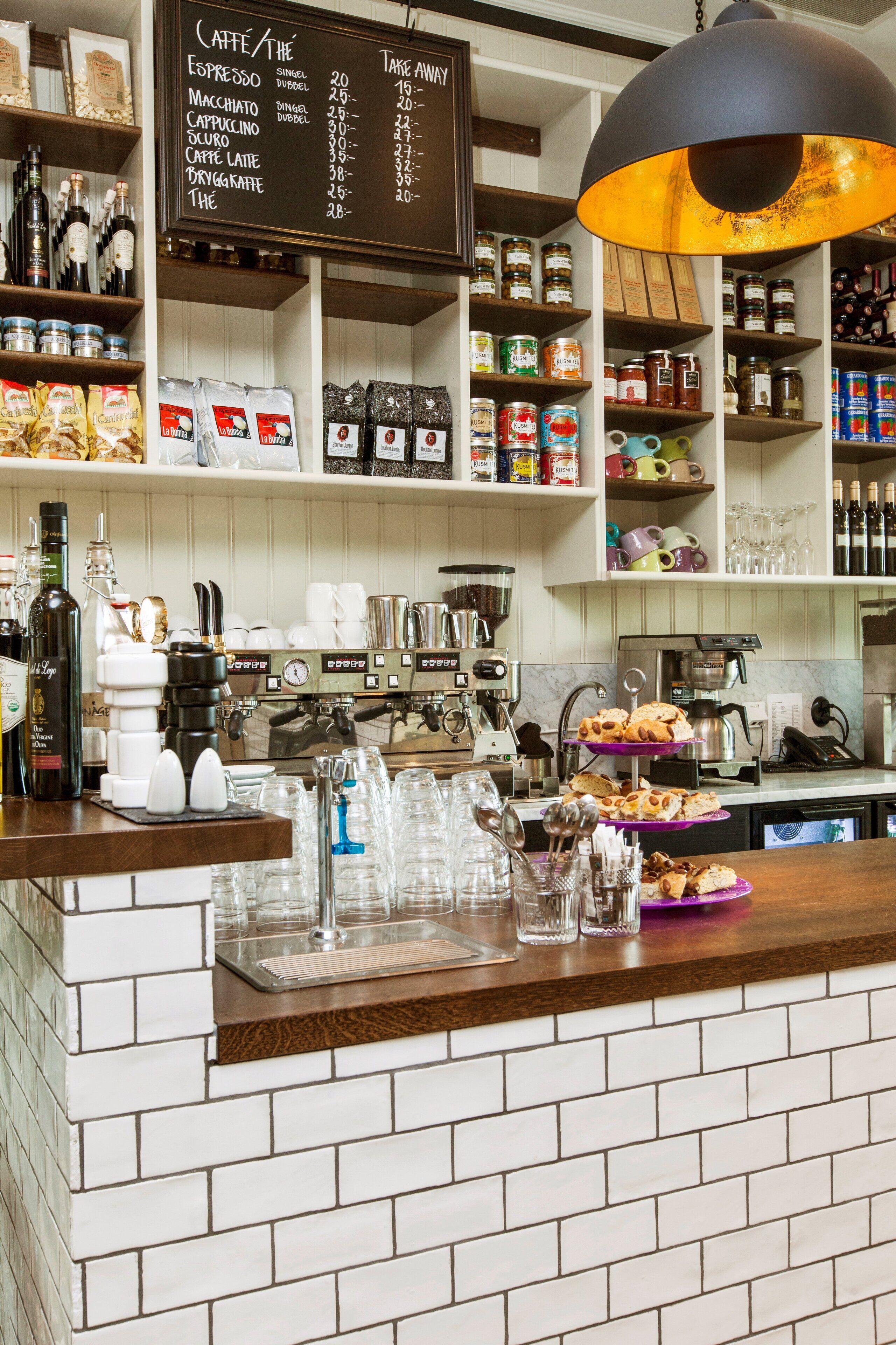 A coffee shop counter with a menu board above, shelves with coffee beans and jars, and a coffee machine.