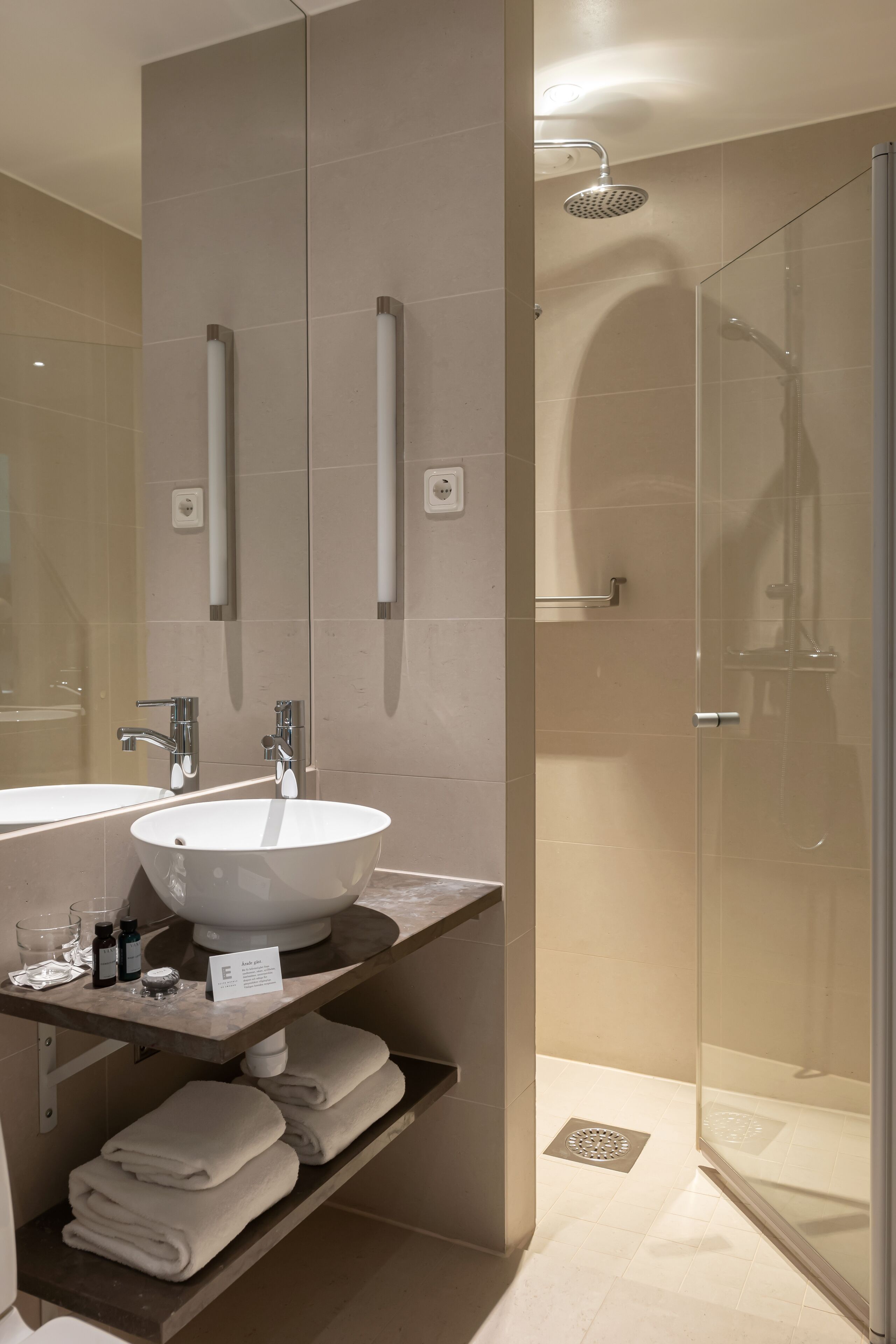 A modern bathroom with two sinks, a glass shower enclosure, and a towel rack.