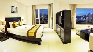 Habitación de hotel moderna con una cama grande, televisión, escritorio y vistas a la ciudad.