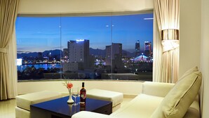 Una sala de estar moderna con un amplio ventanal que ofrece vistas a la ciudad al atardecer.