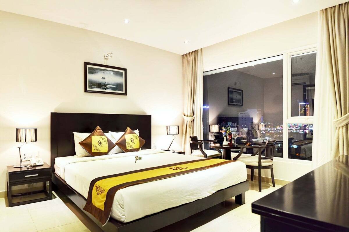 Une chambre d’hôtel avec un grand lit, un bureau et une vue sur la ville.