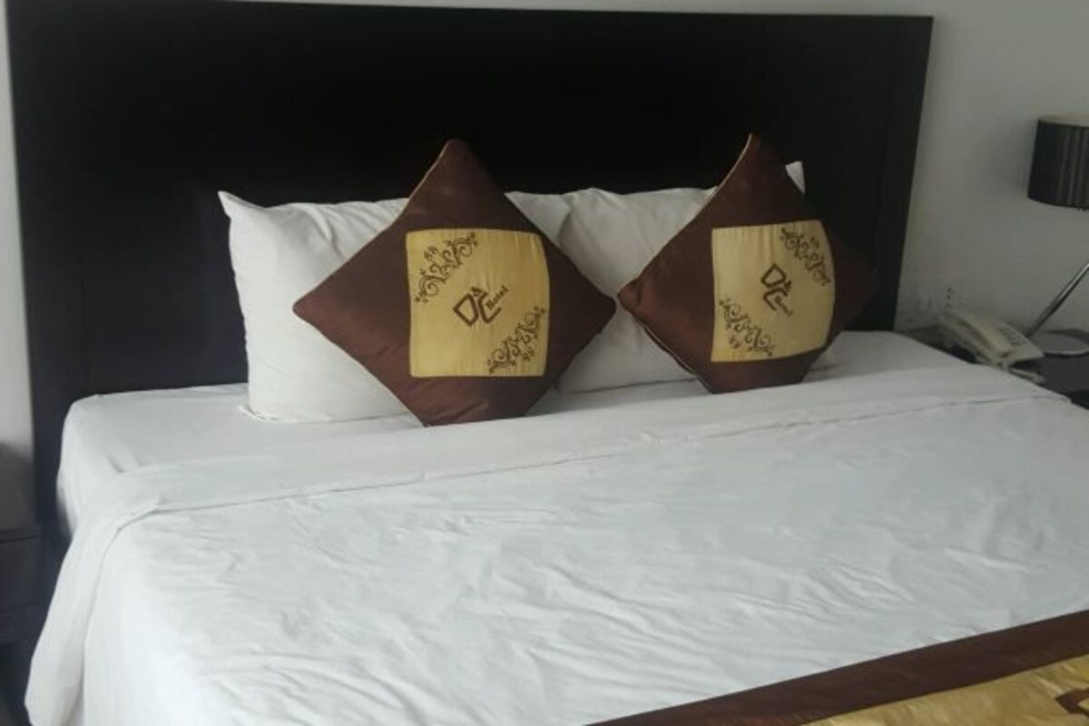 A neatly made bed with white linens and two decorative pillows with gold and brown patterns.