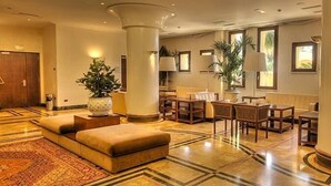 A spacious lobby with a marble floor, a seating area with a sofa and chairs, and large columns. - Cala del Porto (Vibo Valentia)