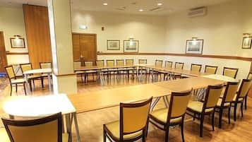 Uma sala de conferências com uma mesa comprida e cadeiras, paredes de madeira e quadros nas paredes.