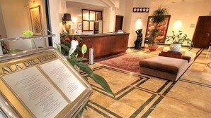 A hotel lobby with a reception desk, a seating area, and a sign with text. - Cala del Porto (Vibo Valentia)