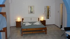Ein Schlafzimmer mit einem hölzernen Bett, zwei Nachttischen mit Lampen, einem gerahmten Bild an der Wand und einem Spiegel.