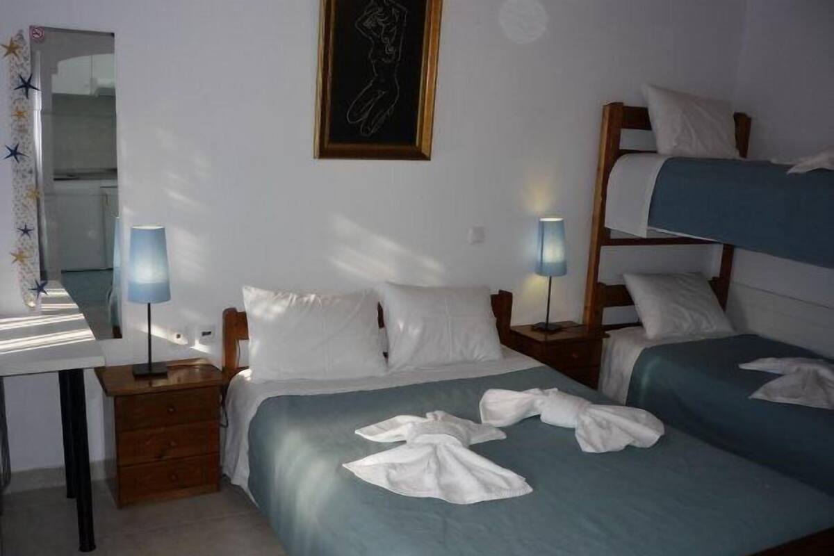 A hotel room with two beds, a desk, and a mirror.