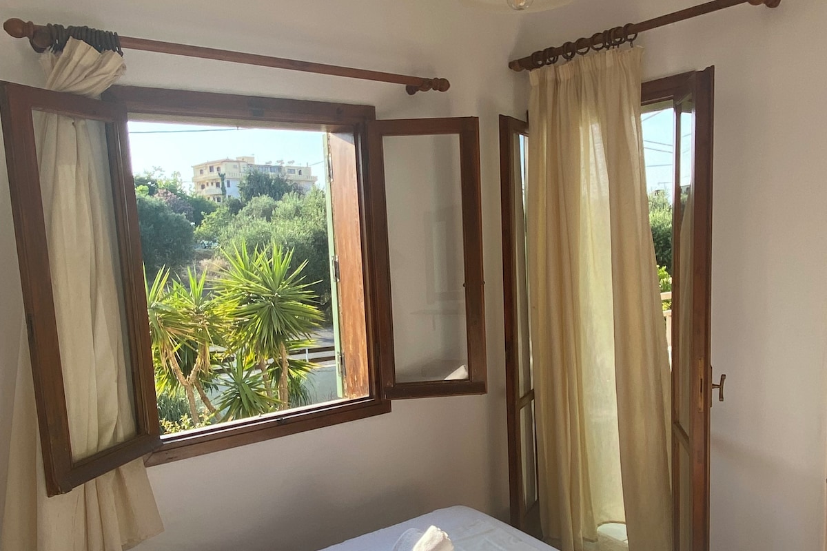 Un dormitorio con dos camas, una ventana con cortinas, un espejo y vistas a zonas verdes.