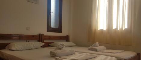 Una habitación de hotel con dos camas, una ventana con cortinas y un interruptor de luz en la pared.