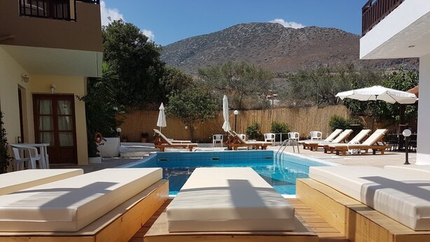 A pool area with lounge chairs and a wooden deck. - Sirocco Apartments (Hersonissos)