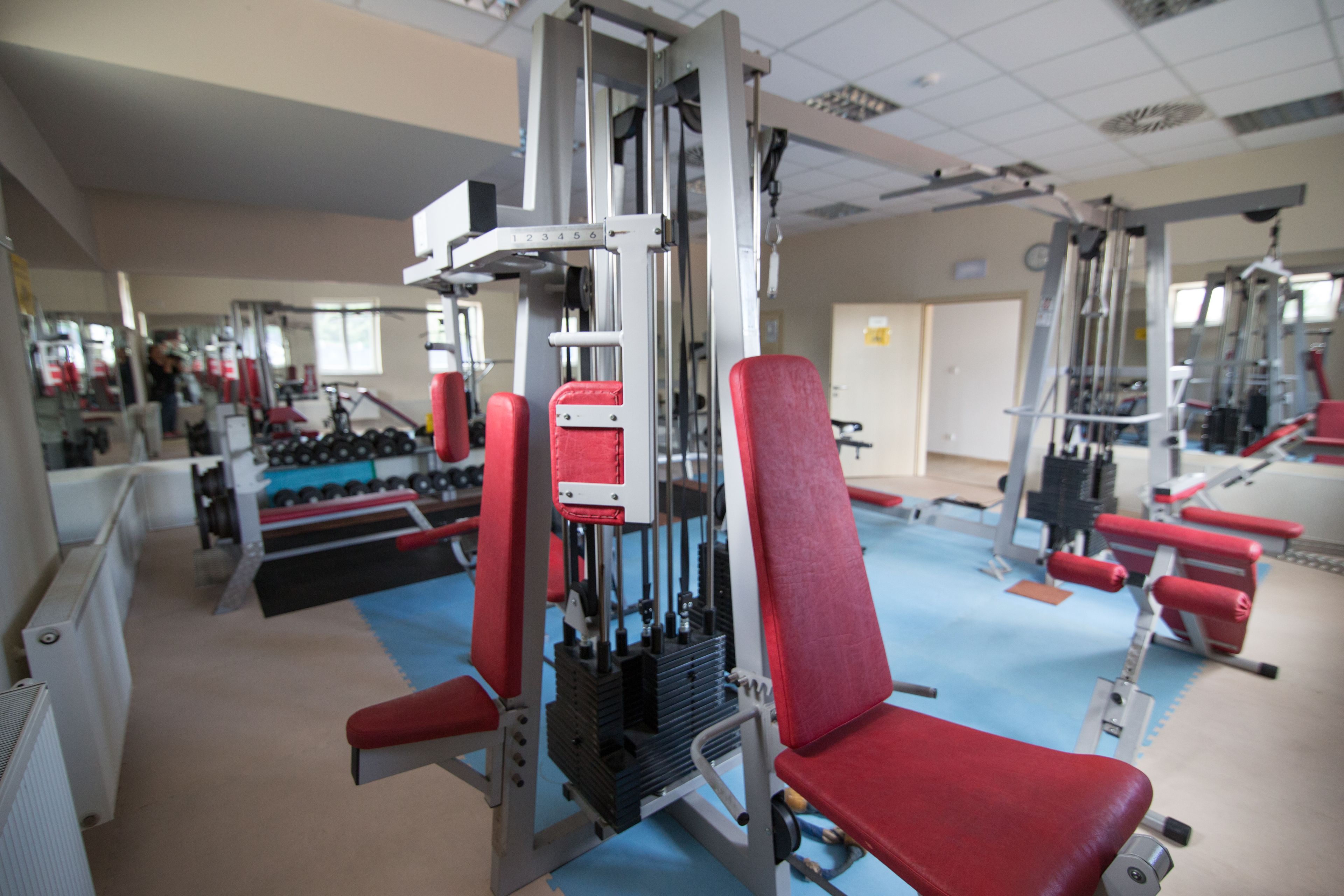 A gym with exercise equipment, mirrors, and a blue floor.