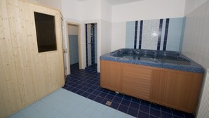 Un baño con puerta de madera, bañera de hidromasaje y paredes con azulejos azules.