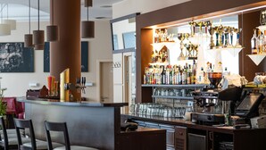 Una zona de bar con mostrador, sillas y una variedad de botellas y vasos.