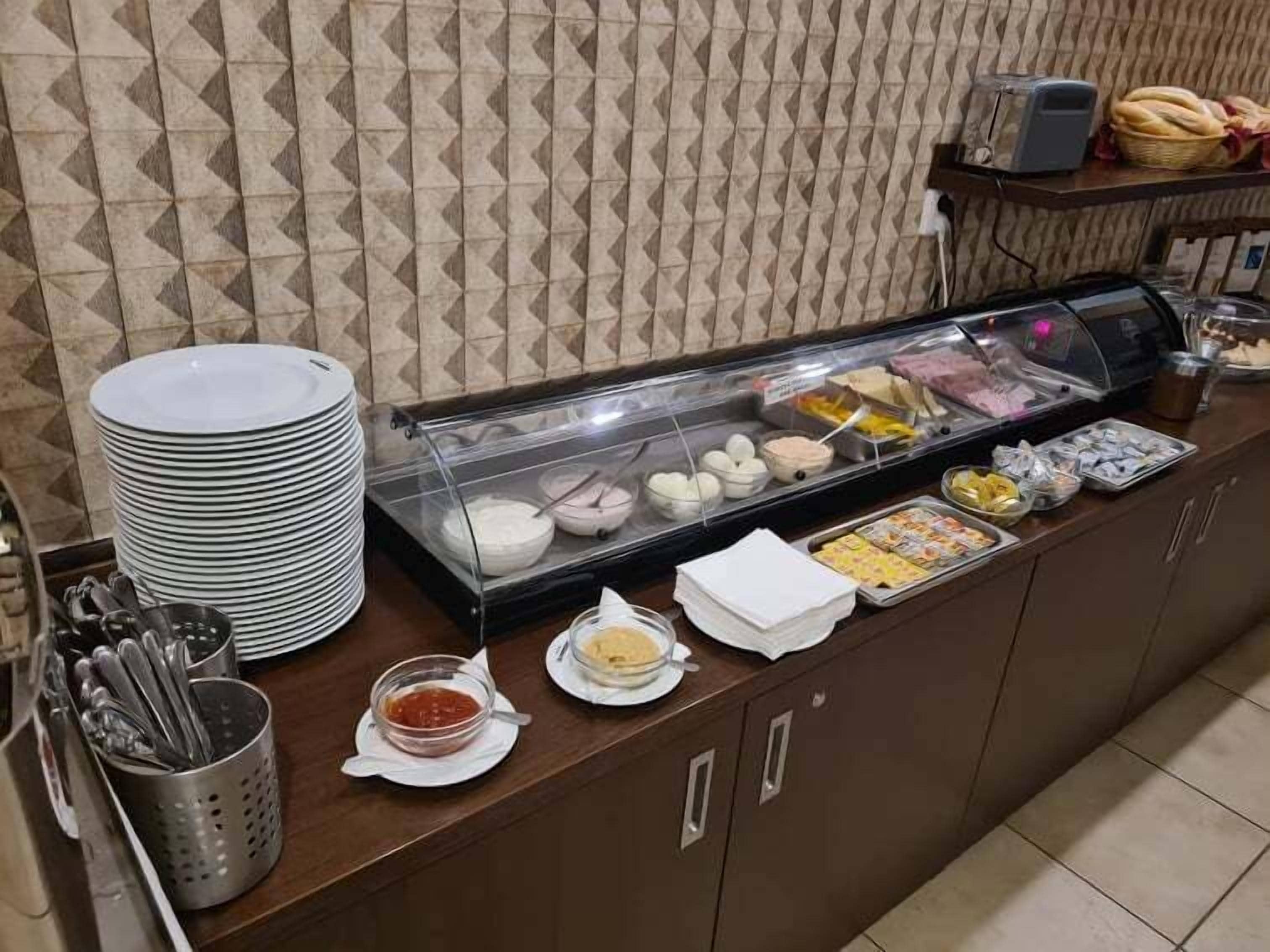 A buffet setup with various food items, plates, and utensils.