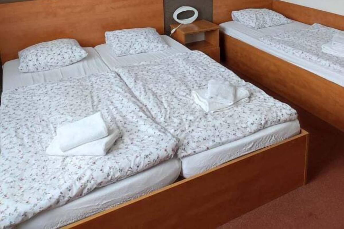 A hotel room with two beds, each with floral-patterned bedding and white pillows.