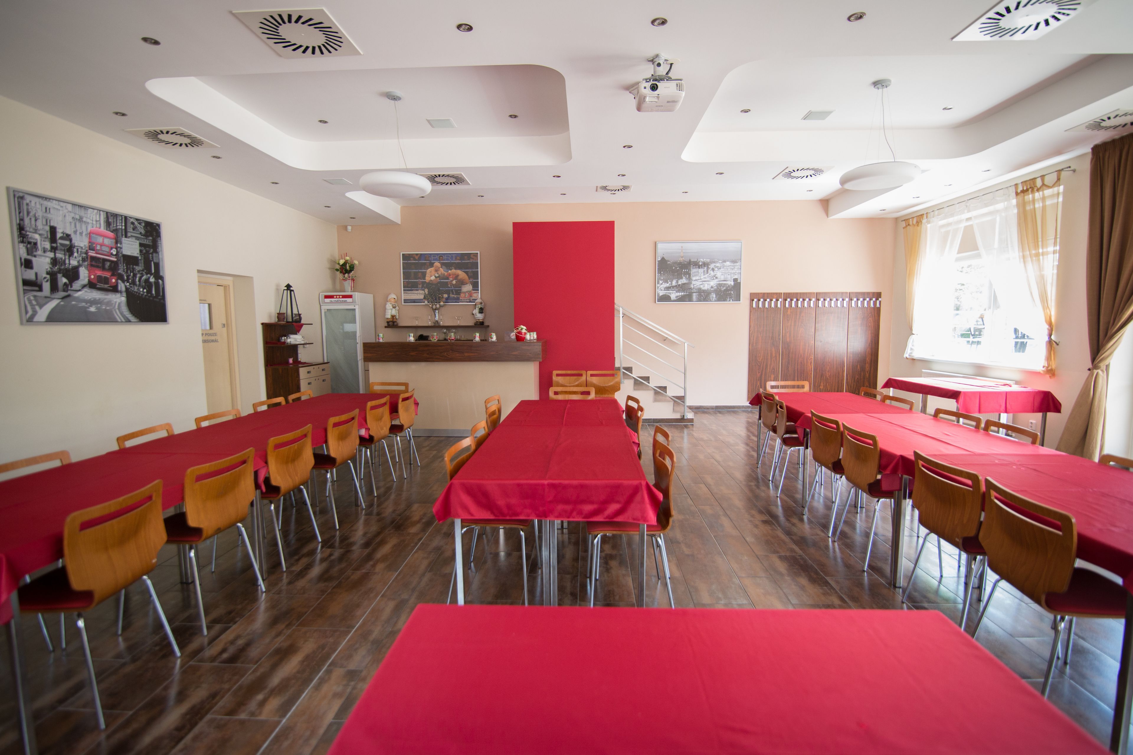 A conference room with long tables and chairs, a red accent wall, and artwork on the walls.
