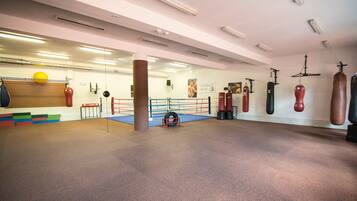 Ein Fitnessstudio mit Boxringen, Sandsäcken und Trainingsgeräten.