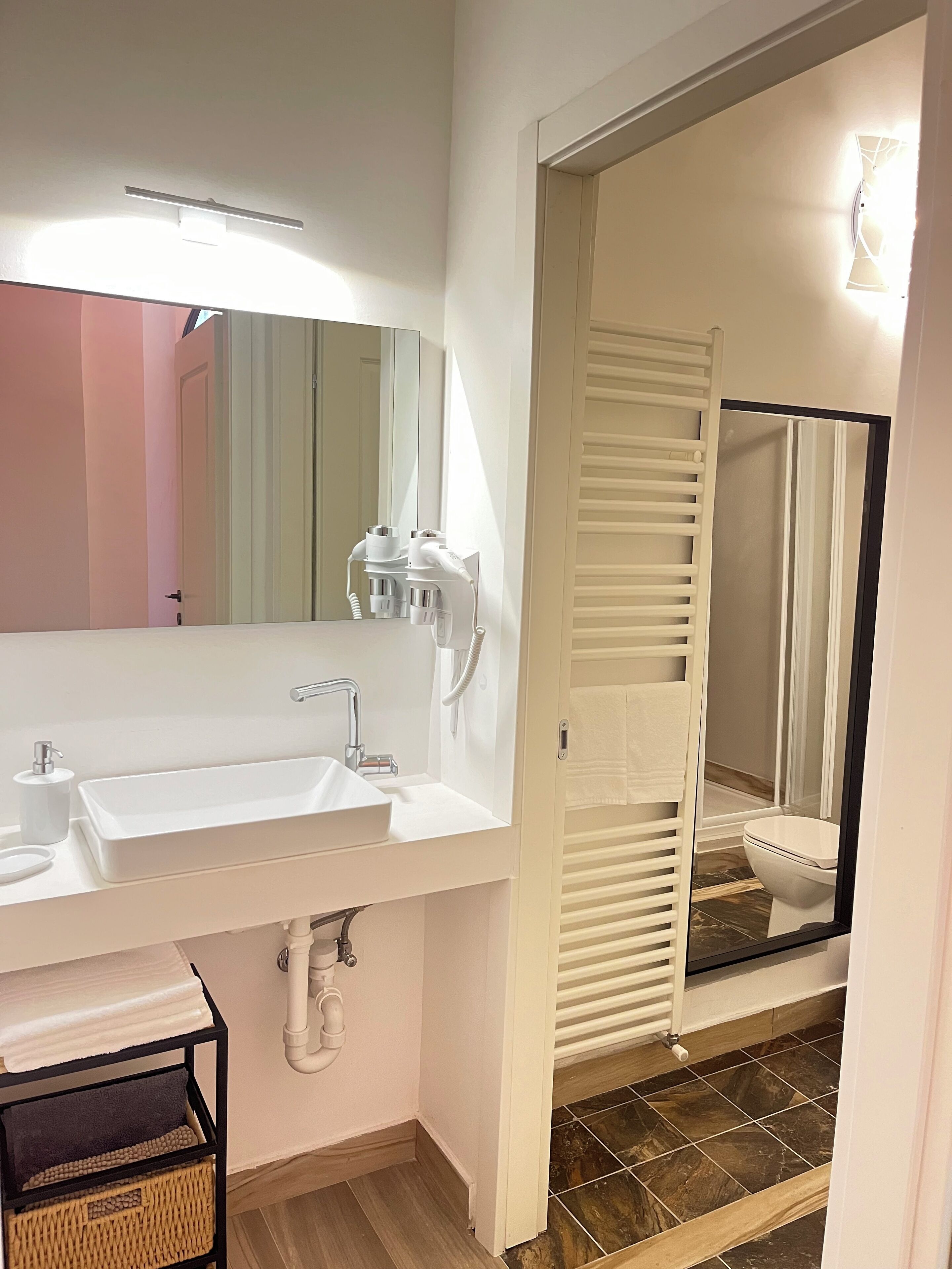Un baño moderno con lavamanos, espejo y toallero blancos.