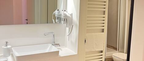 Un baño moderno con lavamanos, espejo y toallero blancos.