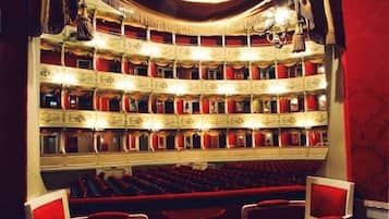 Monitasoinen teatteri, jossa on riveittäin punaisia istuimia ja koristeellisia arkkitehtonisia yksityiskohtia.