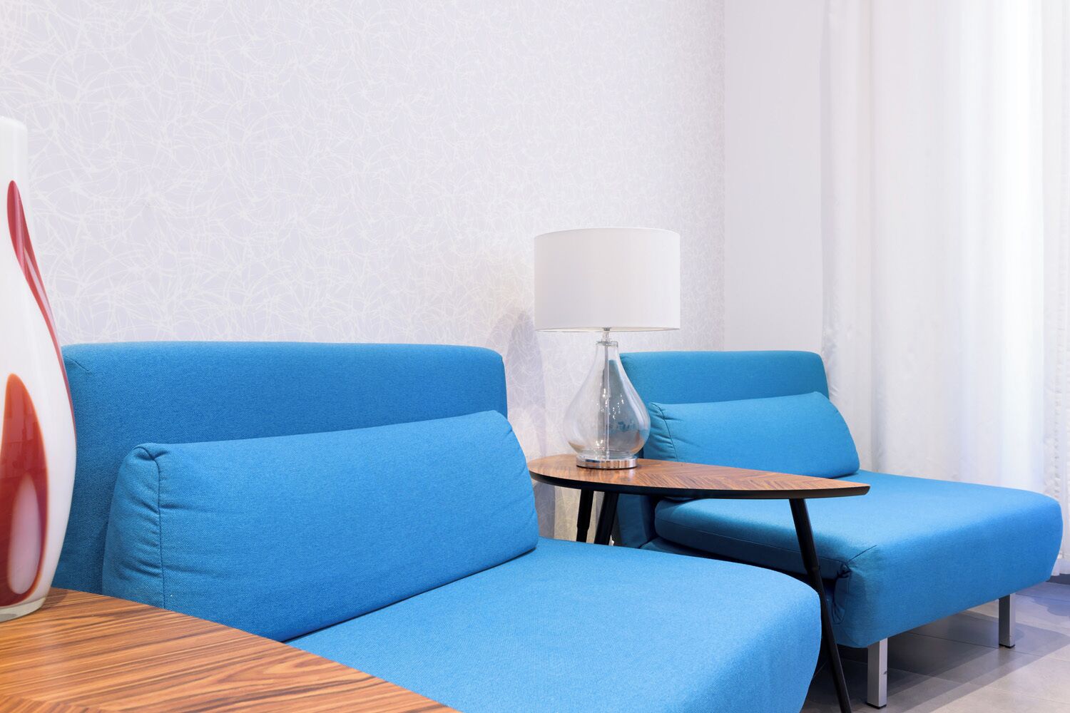 A modern room with a blue sofa, a small wooden table, and a lamp.